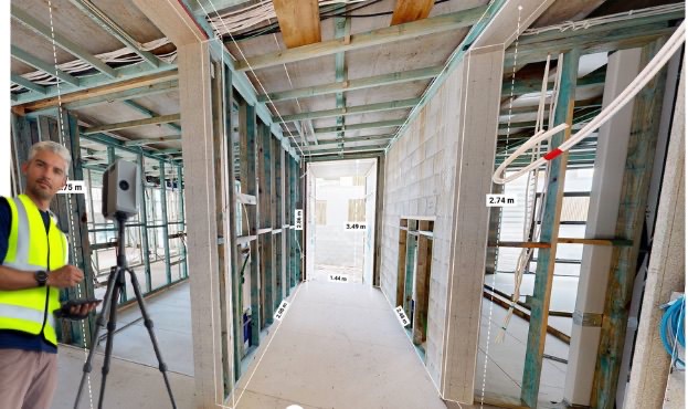 Louis Pont on site with a laser scanner in a framed house